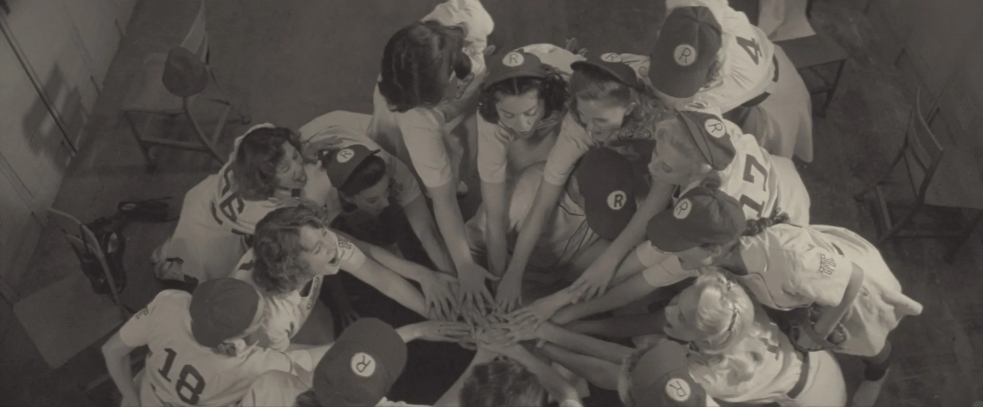 The Rockford Peaches put their hands together in a huddle in A League of Their Own